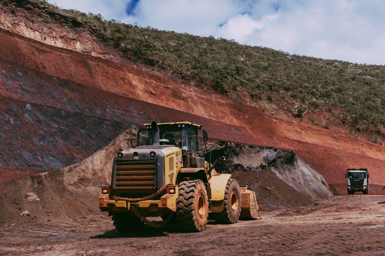 Large yellow tractor on a rugged construction site in a mountainous landscape.