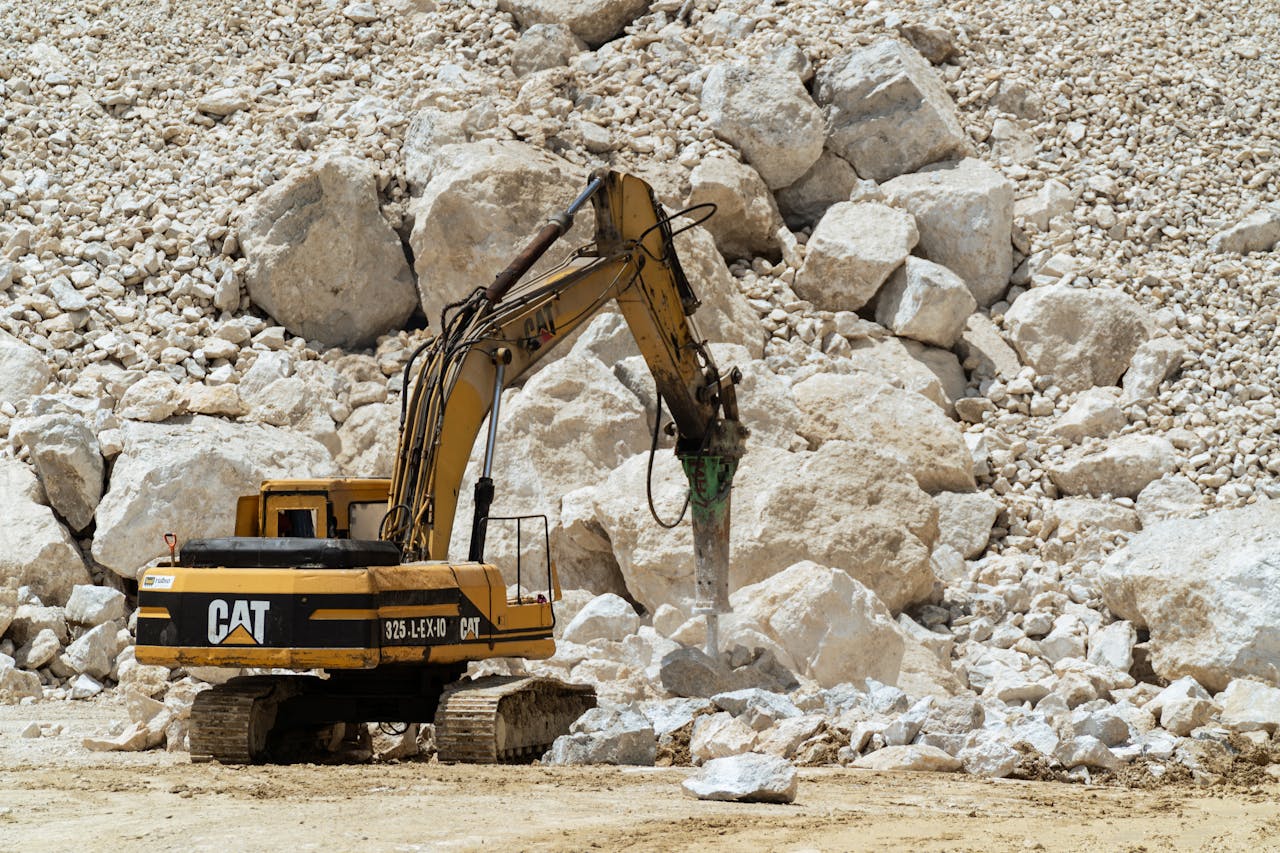 Excavator breaking rocks in a quarry, showcasing heavy-duty industrial work.